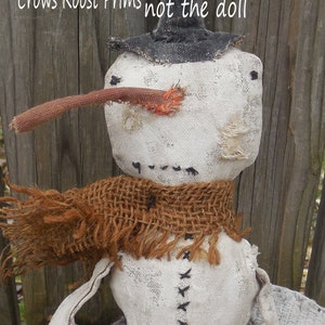 May include: A white fabric snowman doll with a black top hat, brown burlap scarf, and a brown fabric nose. The doll is sitting on a patterned fabric. The text "PATTERN ONLY - Crows Roost Prims not the doll" is written on the background.