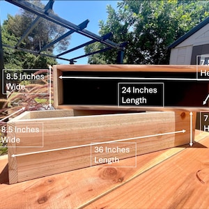 May include: Two rectangular wooden planters, one on top of the other. The top planter is 24 inches long, 8.5 inches wide, and 7.5 inches high. The bottom planter is 36 inches long, 8.5 inches wide, and 7.5 inches high. Both are made of light-colored wood.