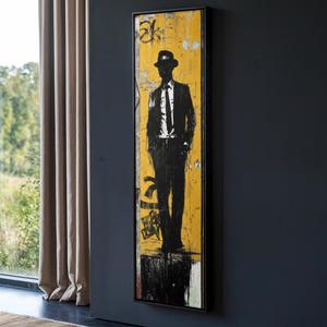 Könnte beinhalten: Eine schwarz-weiße Silhouette einer Person mit Hut und Anzug, die vor einem gelben Hintergrund mit schwarz-weißen Graffiti steht.