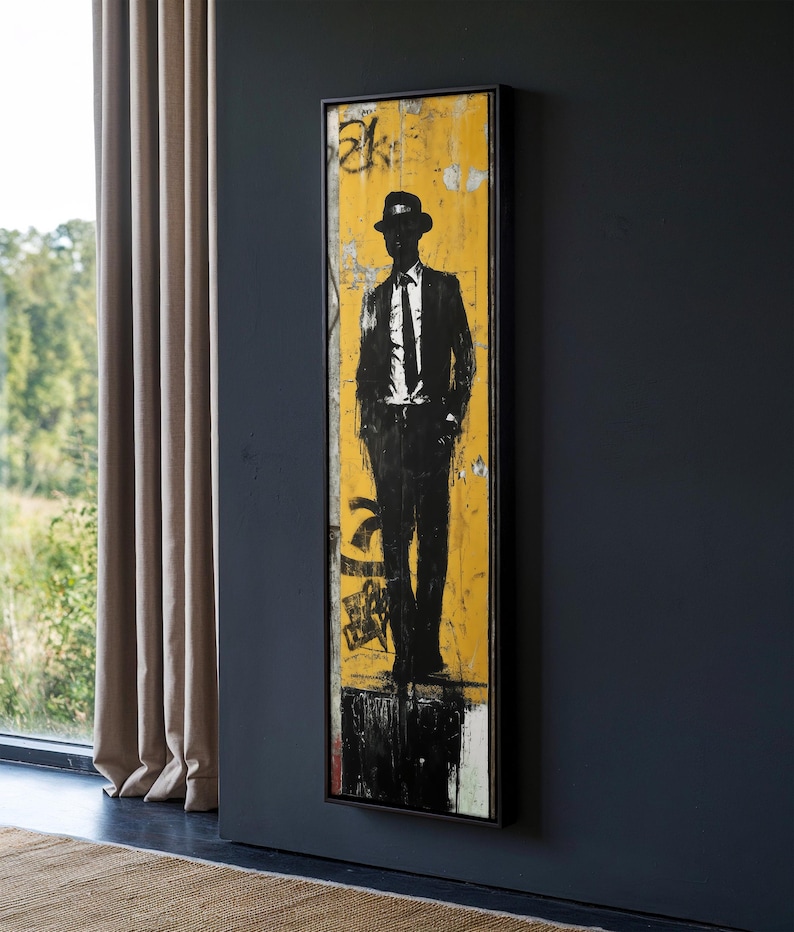 May include: A black and white silhouette of a person wearing a hat and suit standing in front of a yellow background with black and white graffiti.