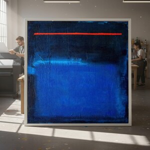 Puede incluir: Gran pintura abstracta en un marco blanco. La obra presenta una sección superior azul oscuro, una sección inferior azul brillante y una fina línea horizontal roja. La pintura se exhibe en un estudio bien iluminado.
