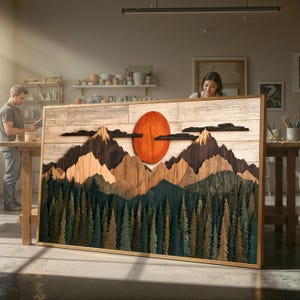 以下が含まれることがあります： 層状の山岳風景を描いた長方形の木製ウォールアート。大きなオレンジ色の太陽、ダークブラウンの山の頂、そして緑と青緑色の松の木が密集する森が、明るい木板の背景に配置されています。