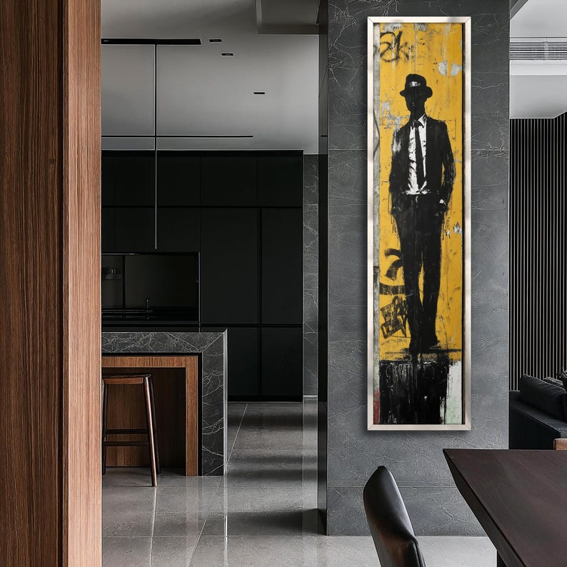 May include: A black and white illustration of a person wearing a hat and suit standing on a yellow and black background. The artwork is framed and hanging on a wall in a modern interior.
