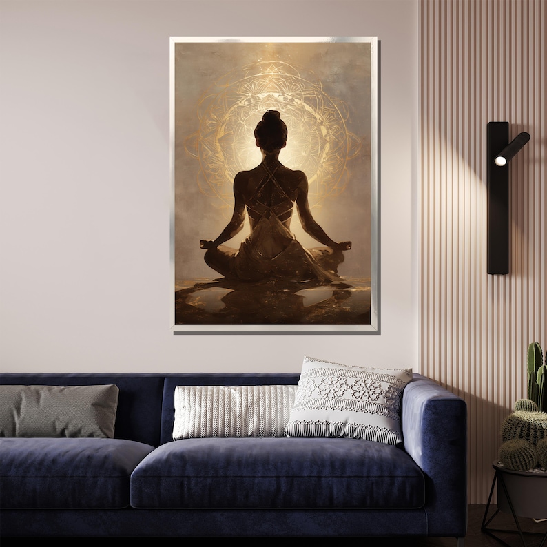 May include: A framed art print depicts a person in a meditative pose, silhouetted against a golden, circular design. The figure is seated in the lotus position, with arms outstretched. The artwork is displayed above a navy blue sofa.