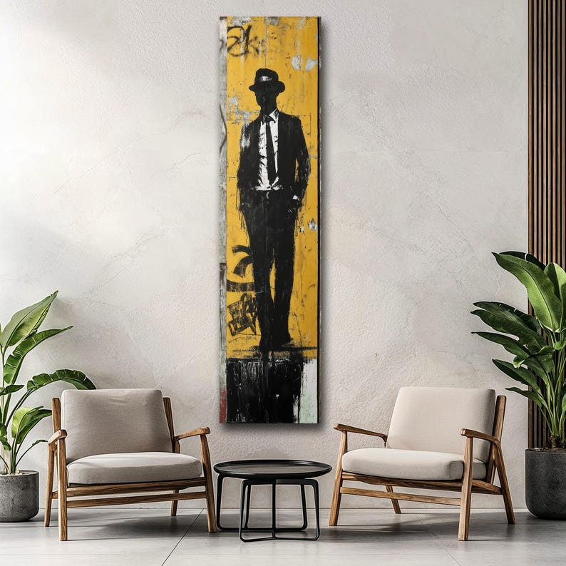 May include: A black and white silhouette of a person wearing a hat and suit standing in front of a yellow background with black and white graffiti.