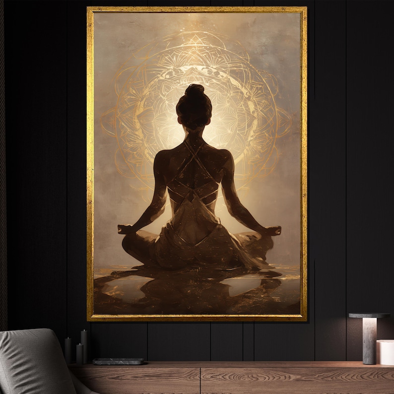 May include: A framed artwork depicts a person in a meditative pose, seated with legs crossed and arms outstretched. The figure is silhouetted against a golden, circular design. The artwork is framed in gold and set against a dark background.