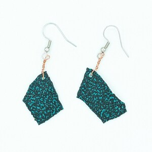 May include: Teal blue and black patterned earrings with silver hooks and copper wire accents.