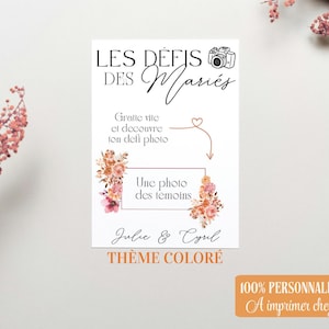 Könnte beinhalten: Eine weiße Karte mit dem Text "LES DÉFIS DES Mariés" und einer Kamera-Illustration. Sie enthält die Sätze "Gratte vite et découvre ton défi photo" und "Une photo des témoins." Die Karte ist mit floralen Elementen und den Namen "Julie & Cyril" verziert.