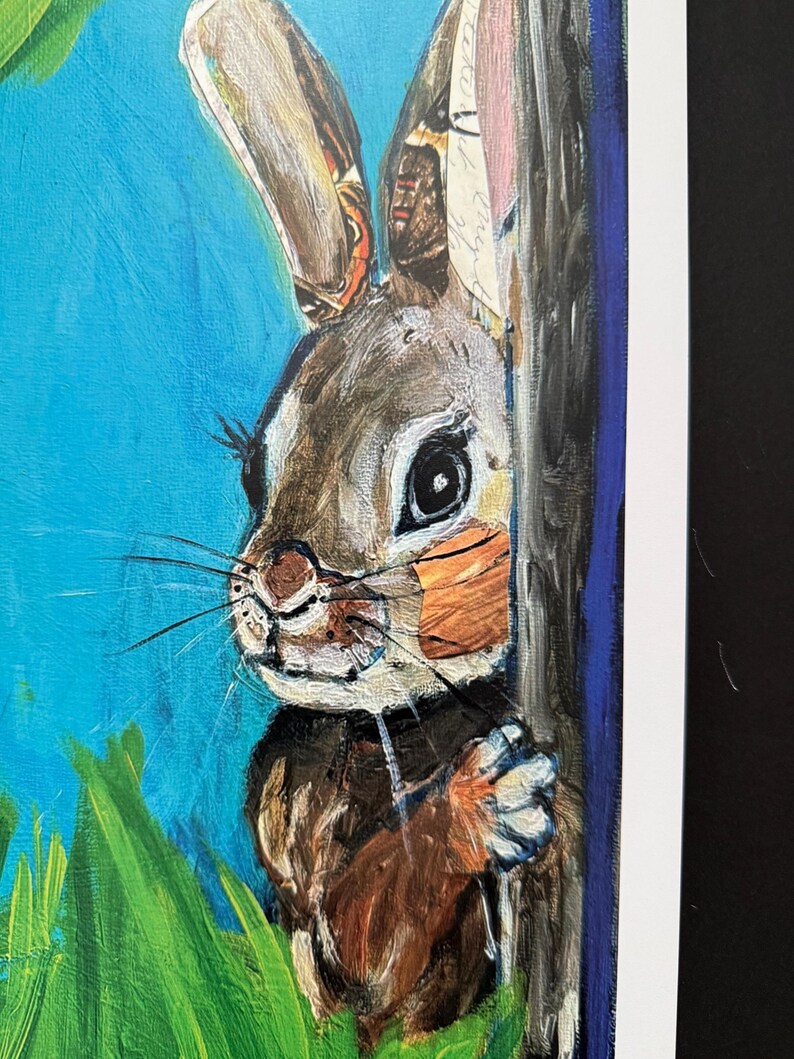 Op de afbeelding: Een schilderij van een bruin en wit konijn dat achter een boom vandaan gluurt. Het konijn heeft lange oren met gedetailleerde patronen. De achtergrond is blauw met groen gras.