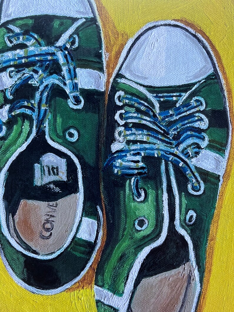 May include: A pair of green canvas sneakers with white laces and white trim. The laces are tied in a criss-cross pattern and the shoes are sitting on a yellow background.