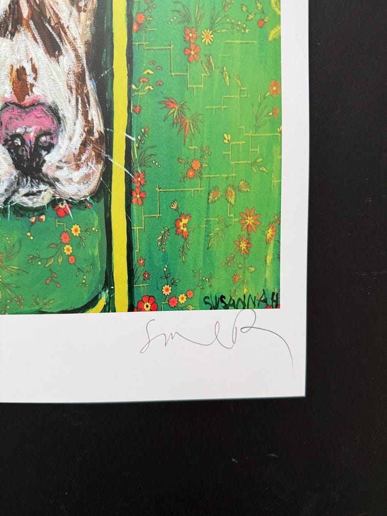 May include: A print featuring a close-up of a dog's snout with a pink nose and brown markings. The background is a vibrant green with a pattern of small orange flowers and thin yellow lines. The name Susannah and a signature are visible at the bottom.