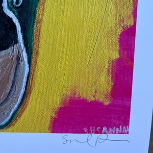 May include: A colorful abstract painting with a green, brown, and white duck on the left side. The background is yellow with a pink and white abstract design. The painting is signed "Susan" in the bottom right corner.