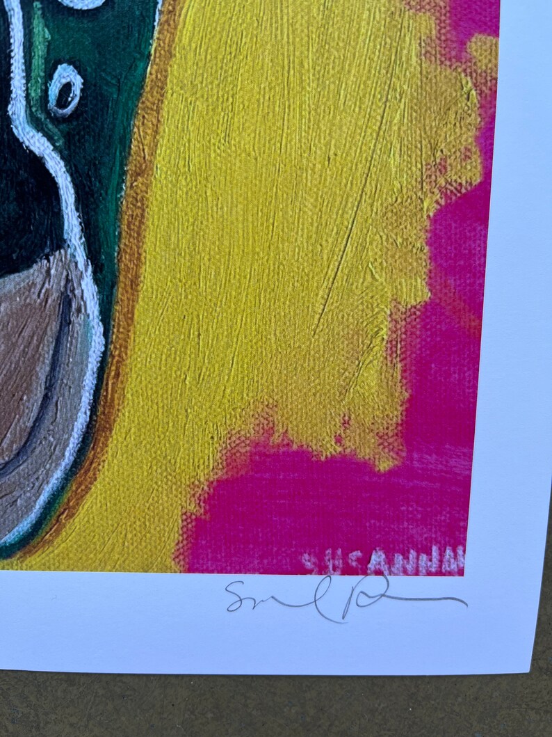 May include: A colorful abstract painting with a green, brown, and white duck on the left side. The background is yellow with a pink and white abstract design. The painting is signed "Susan" in the bottom right corner.