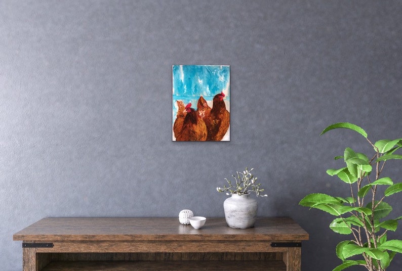 Op de afbeelding: Een schilderij van drie bruine kippen met rode kammen die voor een blauwe en witte achtergrond staan.
