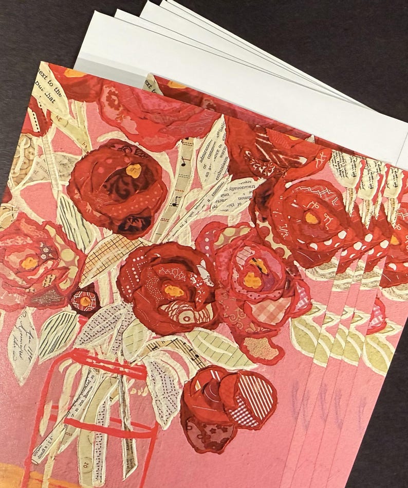 May include: A stack of greeting cards featuring a collage of red roses in a vase. The roses are made from various patterned fabrics and paper, set against a pink background. White envelopes are visible.