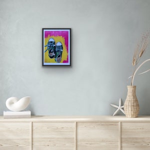 May include: A framed painting of two green sneakers with white laces on a yellow and pink background.