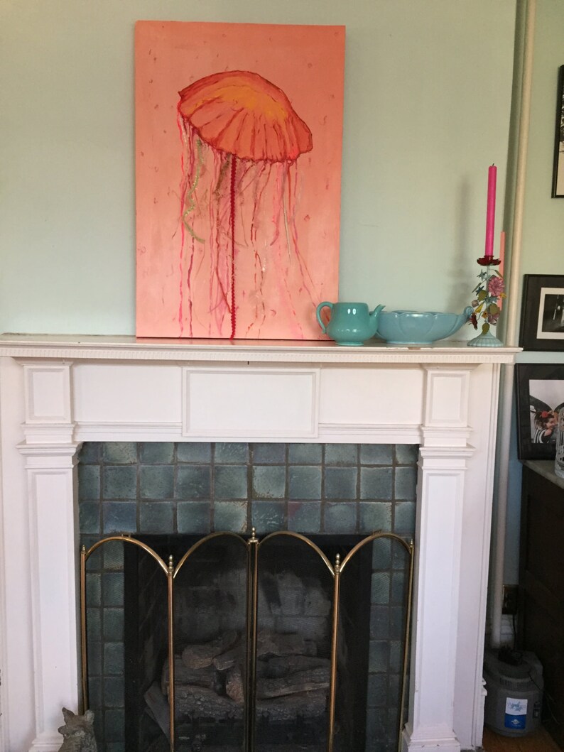 May include: A painting of a pink jellyfish with a yellow bell hanging above a white fireplace with a green tile surround and a brass screen.