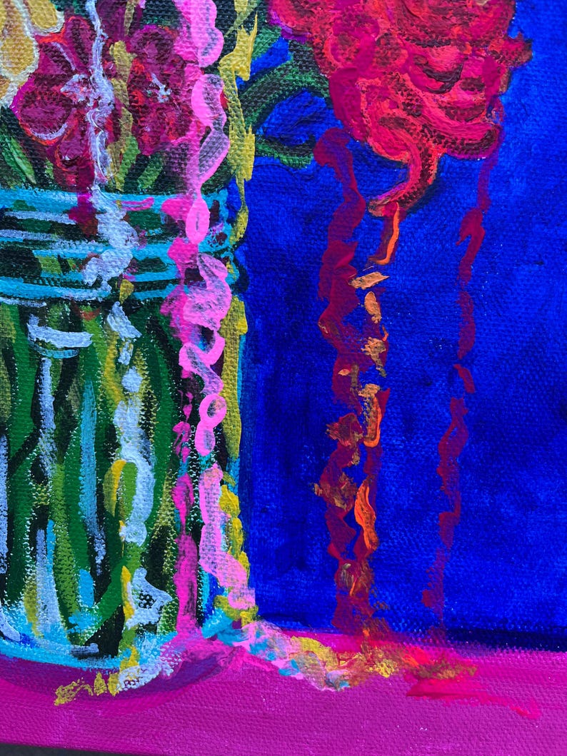 May include: A close-up of a colorful painting of flowers in a glass jar. The flowers are pink, red, and yellow. The jar is green and white. The background is blue.