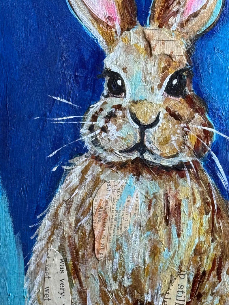 Peut inclure: Peinture en gros plan d'un lapin au pelage brun et blanc, sur fond bleu vif. Le visage du lapin est d&eacute;taill&eacute; avec des yeux noirs, de longues moustaches et des oreilles bord&eacute;es de rose. L'&oelig;uvre int&egrave;gre des &eacute;l&eacute;ments de collage avec des fragments de texte visibles.