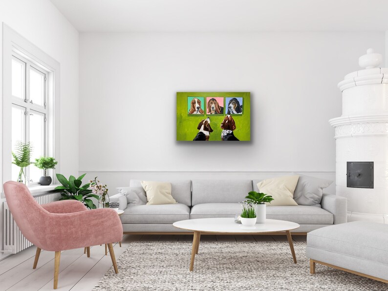 May include: A modern living room with a white wall, a gray sofa, and a pink armchair. Above the sofa, four framed dog portraits hang on a green background. A white coffee table and a white fireplace complete the room's decor.