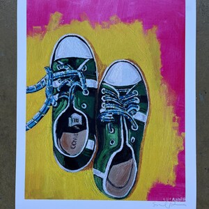 May include: A painting of a pair of green canvas sneakers with white laces and white trim. The sneakers are on a yellow background with a pink border.