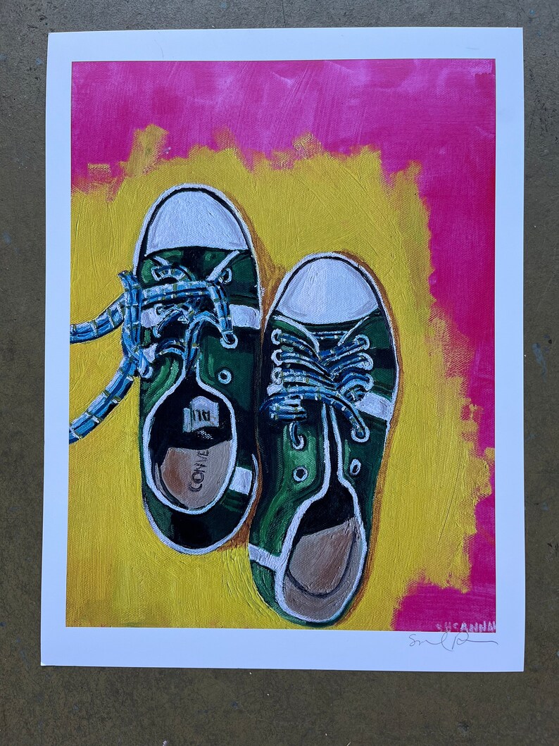 May include: A painting of a pair of green canvas sneakers with white laces and white trim. The sneakers are on a yellow background with a pink border.