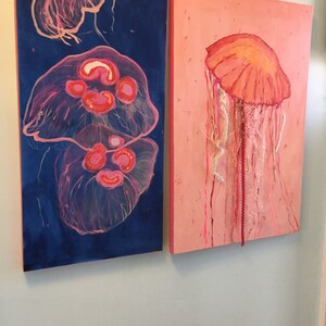 May include: Two paintings of jellyfish, one with a blue background and two jellyfish, the other with a pink background and one jellyfish.