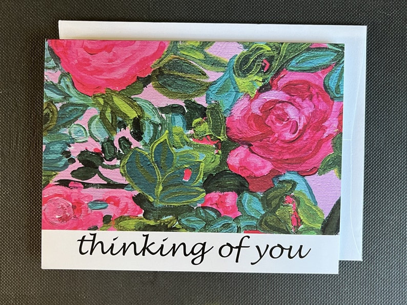 May include: A pink and green floral greeting card with the text "thinking of you" in black.