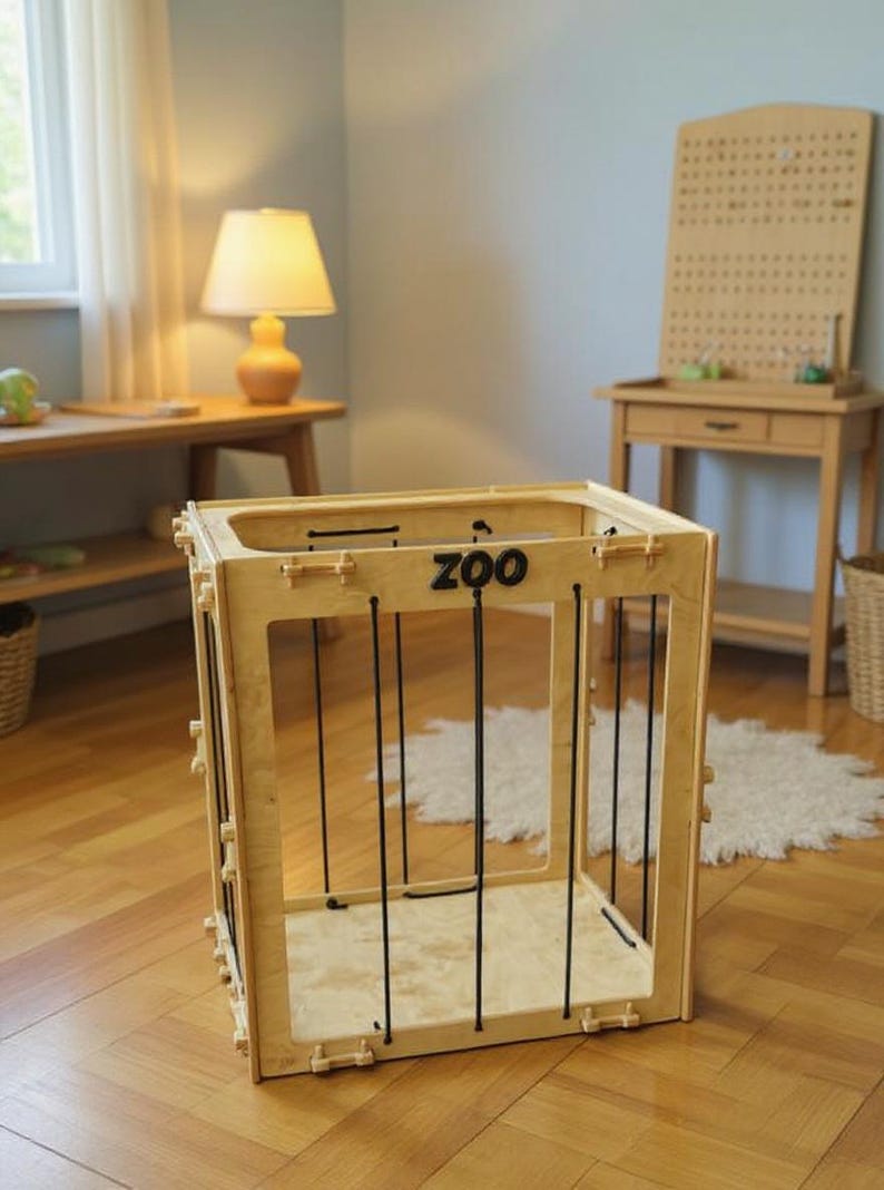 Op de afbeelding: Een houten speelstructuur met het woord "ZOO" op de voorkant. De structuur heeft een kooi-achtig ontwerp met zwarte verticale staven. Het frame is gemaakt van lichtgekleurd hout. De structuur is ontworpen voor kinderspel.