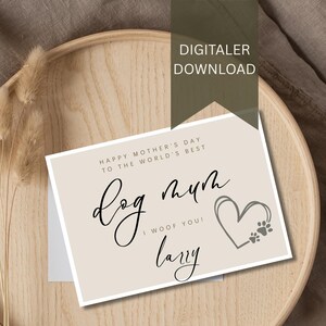 Könnte beinhalten: Eine beige Muttertagskarte mit dem Text "Dog Mum" und "I Woof You!" in schwarzer Schrift. Rechts befindet sich ein Herz mit Pfotenabdrücken. Die Karte liegt auf einem Holztablett mit getrockneten Pflanzen. Oben steht "DIGITALER DOWNLOAD".