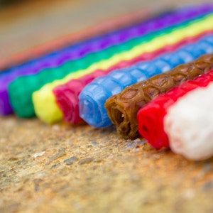 Candles of a variety of colors displayed to show their bottoms. Candles fit a standard Waldorf ring, and can also be used as birthday candles.