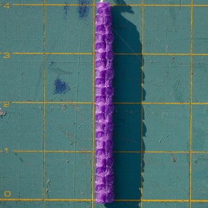 Image shows one candle lying on a mat marked with measurements. Each candle is four inches long.