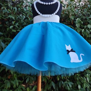 K&ouml;nnte beinhalten: Ein blauer T&uuml;llrock mit einer wei&szlig;en Katzen-Silhouette und einem wei&szlig;en Bund. Der Rock ist auf einem Mannequin und hat einen wei&szlig;en T&uuml;ll-Unterrock.