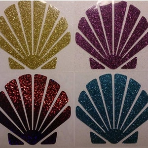 May include: Four glitter seashells in different colors: gold, purple, red and blue. The shells are all the same size and shape, and they are arranged in a grid pattern.