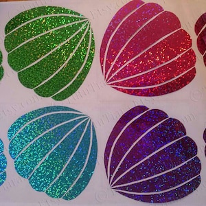 May include: Four iridescent glitter seashell stickers in green, pink, blue, and purple. The stickers are on a white background.