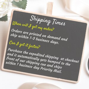May include: Black chalkboard with white text that reads "Shipping Times" and explains the shipping process for orders. The text says "Orders are printed on demand and ship within 1-3 business days." and "Purchase the expedited shipping at checkout and it automatically gets bumped to the front of our shipping cue and ships within 1 business day Priority Mail."