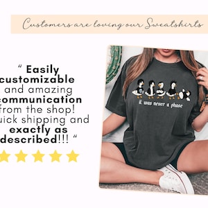 Puede incluir: Sudadera gris oscuro con un gr&aacute;fico de cinco patos de dibujos animados con diferentes peinados y la frase "it was never a phase". El banner superior dice "Customers are loving our Sweatshirts."