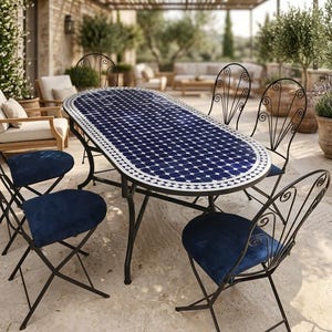 May include: An oval dining table with a blue and white geometric tiled top and black metal frame, accompanied by six black metal chairs featuring scrollwork backrests and solid dark blue seat cushions arranged on a stone patio surface.