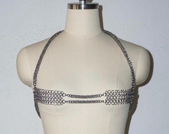 Pode incluir: Um conjunto de biquíni de malha de corrente prateada em um manequim branco.
