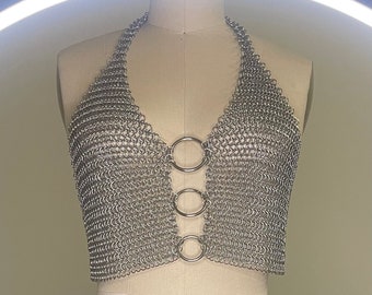 Pode incluir: Um top halter de malha de corrente prateada com três anéis prateados no centro.