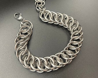 May include: A silver chain bracelet made of interlocking metal rings. The bracelet is made of a durable metal and has a polished finish.