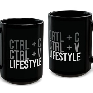 May include: Two black mugs with white text that reads "CTRL + C CTRL + V LIFESTYLE".