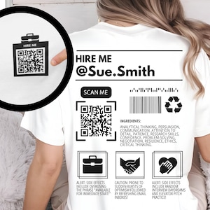 May include: White t-shirt with a black and white design that says "HIRE ME @Sue.Smith". The design includes two QR codes, a barcode, and a recycle symbol. The text "SCAN ME" is also included. The design also includes three icons: a briefcase, two hands shaking, and a heart.