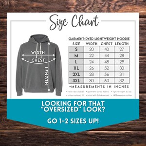 May include: Size chart for a garment-dyed lightweight hoodie. The chart shows the width, chest, and length measurements in inches for sizes S through 3XL. The chart also includes information about the fabric and fit of the hoodie. The text "Looking for that "oversized" look? Go 1-2 sizes up!" is displayed below the chart.