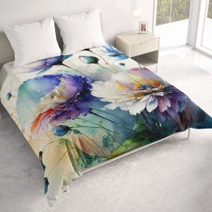 May include: A watercolor-style floral duvet cover featuring large blooms in shades of purple, white, and blue. The bedding set includes two white pillows. The design has a soft, artistic aesthetic, perfect for a bedroom.
