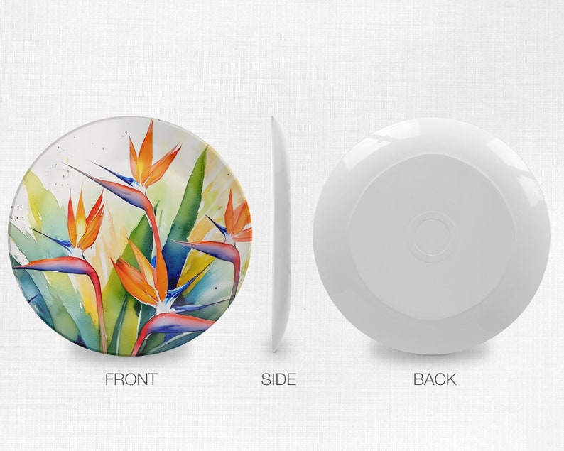 Pu&ograve; includere: Un piatto in ceramica bianca con un design ad acquerello colorato di fiori di uccello del paradiso arancioni, blu e verdi.