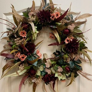Pode incluir: Uma coroa de flores bord&ocirc; e rosa com folhas de eucalipto e detalhes de bagas. A coroa &eacute; feita de flores de seda e &eacute; perfeita para a decora&ccedil;&atilde;o de outono.