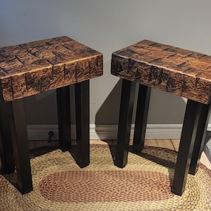 May include: Two wooden end tables with black metal legs. The tables have a rustic, reclaimed wood look and are sitting on a braided rug.