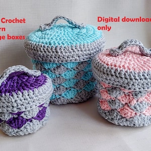 Puede incluir: Tres cajas de almacenamiento de crochet en diferentes tamaños. La caja más grande es azul claro y gris, la caja mediana es rosa y gris, y la caja más pequeña es morada y gris. Descarga digital solamente.