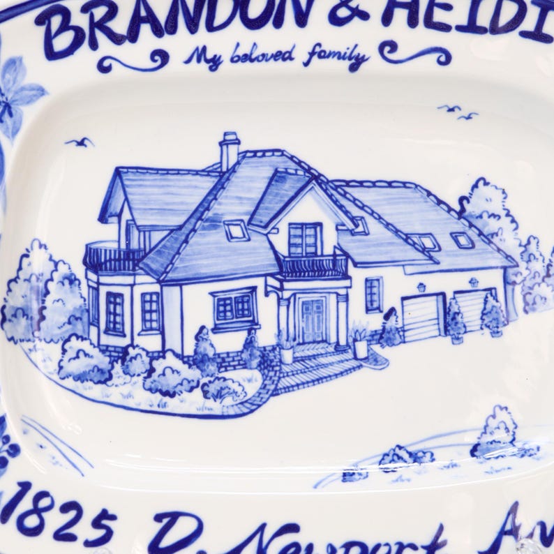 May include: A white rectangular ceramic serving platter with a hand-painted blue illustration of a house. The platter has the text "BRANDON & HEIDI" and "My beloved family" in blue script. The house illustration includes a driveway, trees, and a garage.
